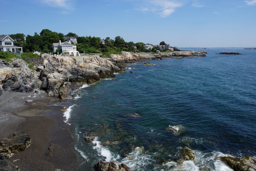 The shoreline of a beach in Marblehead MA with a house in the distance