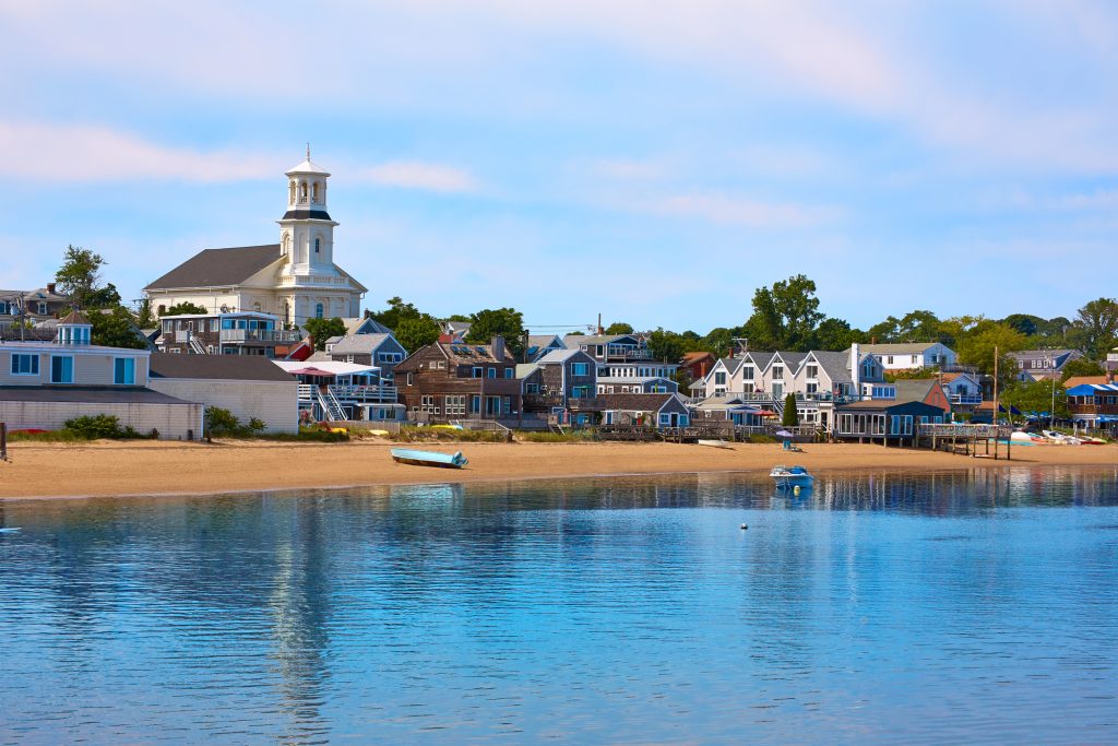 View of provincetown from the water, with a small stretch of beach in front of buildings